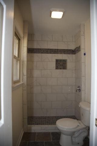 bathroom featuring a tile shower and toilet