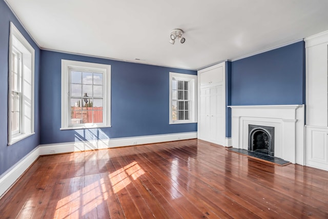 unfurnished living room with hardwood / wood-style flooring and crown molding