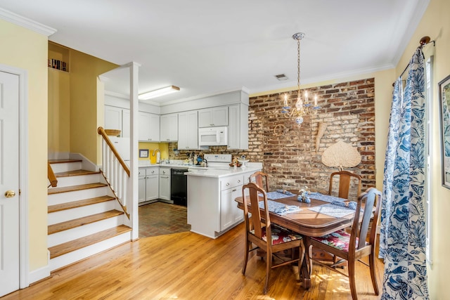 dining area with light hardwood / wood-style flooring, a notable chandelier, ornamental molding, and brick wall