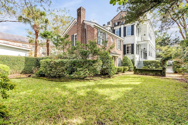 52 Hasell St, Charleston, SC 29401 - view of side of property featuring brick siding, a chimney, a lawn, and a balcony