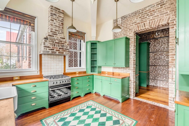 kitchen with wooden counters, light wood-type flooring, hanging light fixtures, and high end black range