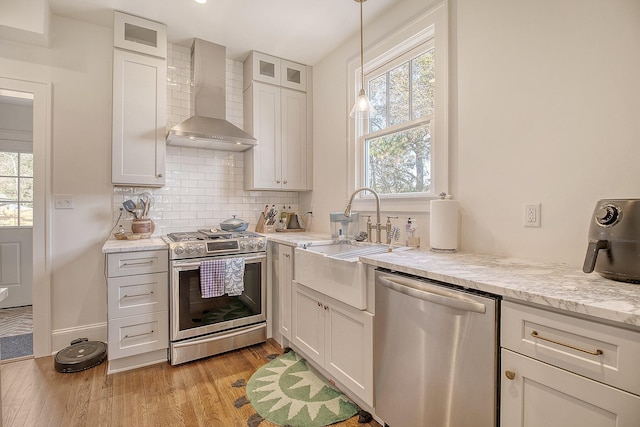 kitchen with white cabinetry, appliances with stainless steel finishes, and wall chimney range hood