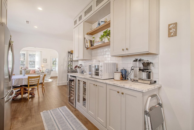 kitchen featuring stainless steel fridge, light stone countertops, and white cabinets