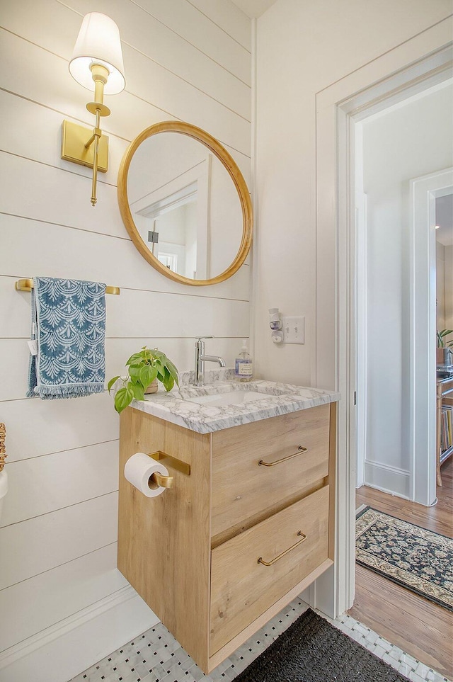 bathroom with tile patterned flooring, vanity, and wooden walls