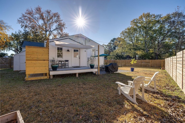 back of property with a yard, a deck, and a storage shed