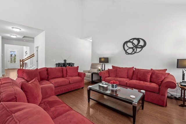 living room featuring wood finished floors, stairway, and a towering ceiling