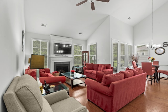 living room with high vaulted ceiling, visible vents, wood finished floors, and ceiling fan with notable chandelier