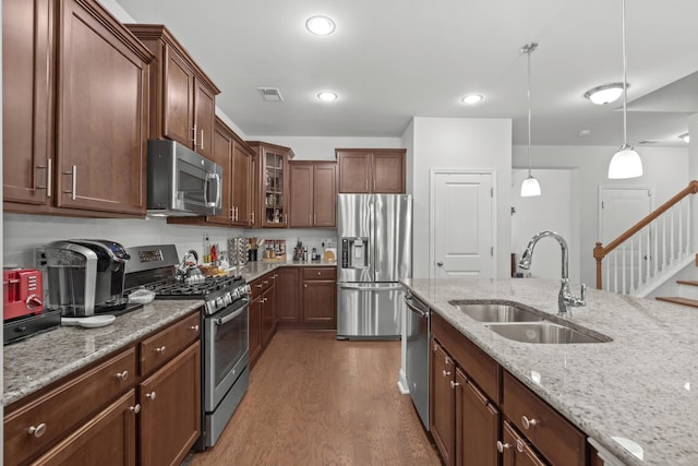 kitchen featuring visible vents, dark wood-style floors, a sink, decorative light fixtures, and stainless steel appliances