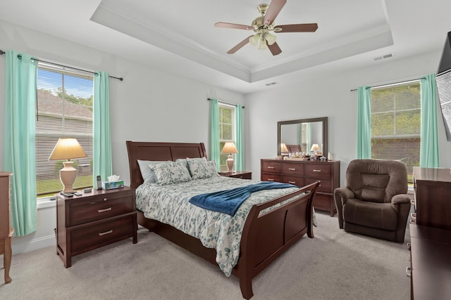 bedroom featuring visible vents, ornamental molding, a tray ceiling, and light colored carpet