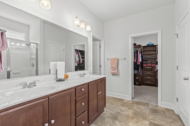 full bath featuring double vanity, a spacious closet, a sink, and a stall shower