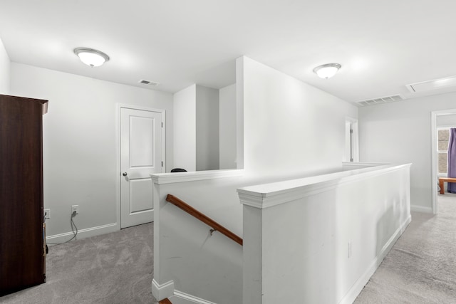 corridor with baseboards, visible vents, carpet, and an upstairs landing