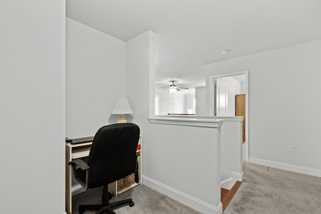 carpeted office space with a ceiling fan and baseboards