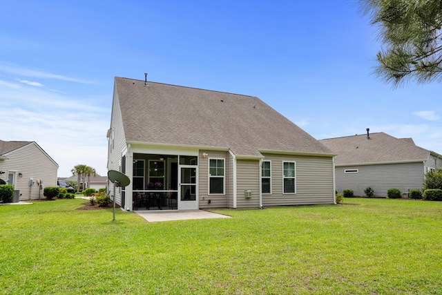 rear view of house featuring a lawn, a patio, a sunroom, and roof with shingles