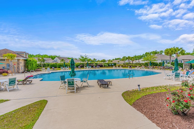 community pool with a patio, fence, and a residential view