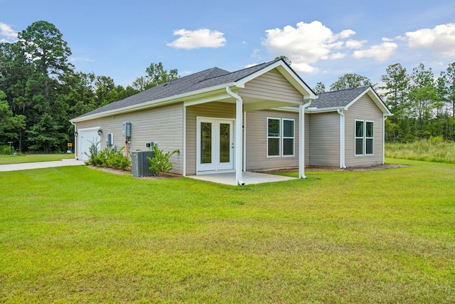 rear view of house featuring a patio, a garage, a yard, and cooling unit