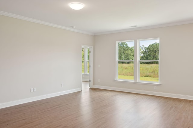 unfurnished room with crown molding, wood finished floors, visible vents, and baseboards