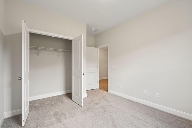 unfurnished bedroom with carpet, a closet, and baseboards