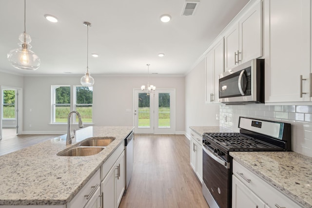 kitchen with stainless steel appliances, white cabinetry, sink, and a kitchen island with sink