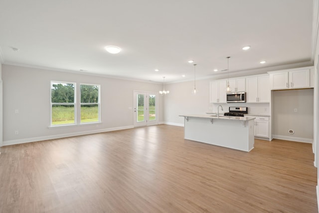 kitchen featuring white cabinetry, a center island with sink, appliances with stainless steel finishes, hanging light fixtures, and light wood-type flooring