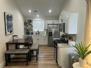 kitchen featuring hardwood / wood-style flooring, appliances with stainless steel finishes, vaulted ceiling, and white cabinets