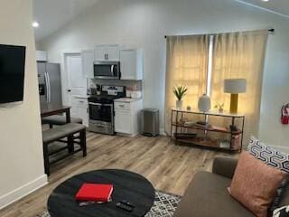 living room featuring light hardwood / wood-style flooring and high vaulted ceiling