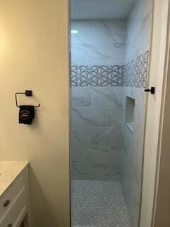 bathroom with vanity and a tile shower