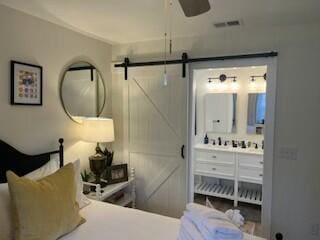 bedroom featuring ensuite bath and a barn door