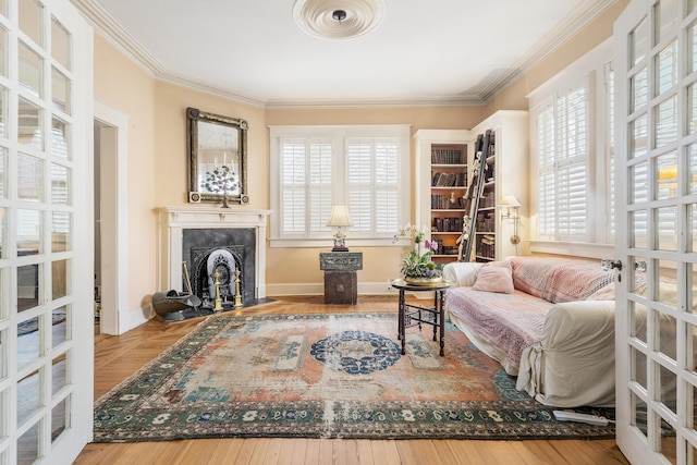 sitting room with crown molding, hardwood / wood-style floors, a high end fireplace, and a healthy amount of sunlight