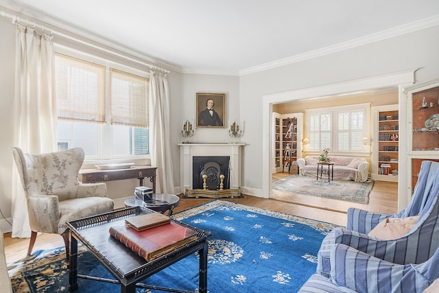 living area featuring a wealth of natural light, a fireplace with raised hearth, crown molding, and wood finished floors