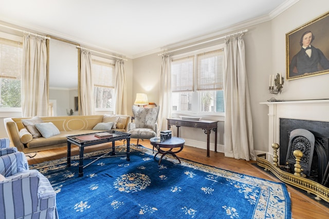 living area featuring baseboards, a fireplace, wood finished floors, and crown molding