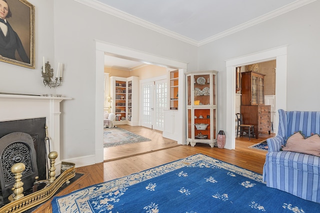 interior space with a fireplace, crown molding, ensuite bath, baseboards, and hardwood / wood-style flooring