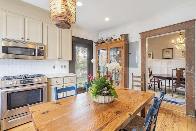 dining space with light wood-style floors, recessed lighting, ornamental molding, and an inviting chandelier