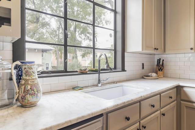 kitchen with light stone counters, backsplash, and a sink