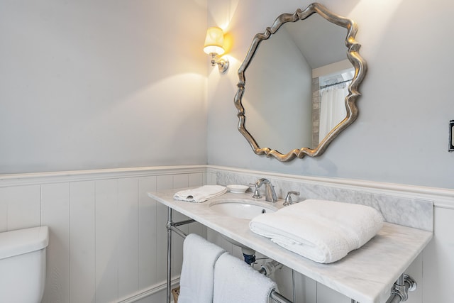 bathroom with a wainscoted wall, vanity, and toilet