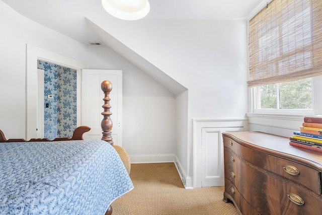 bedroom featuring baseboards, vaulted ceiling, visible vents, and light colored carpet