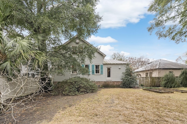 rear view of property with fence, metal roof, and a lawn