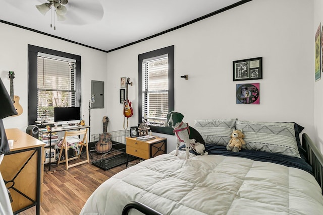 bedroom with ceiling fan, ornamental molding, electric panel, and hardwood / wood-style floors