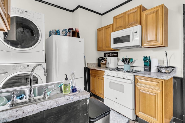 kitchen featuring stacked washing maching and dryer, white appliances, crown molding, and light stone countertops