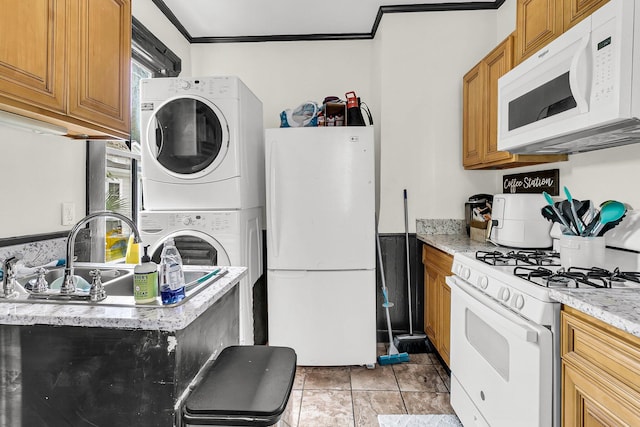 kitchen with stacked washer / dryer, a healthy amount of sunlight, white appliances, and crown molding