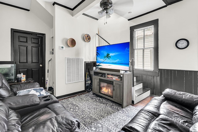 living room featuring ceiling fan, vaulted ceiling with beams, crown molding, and wood-type flooring