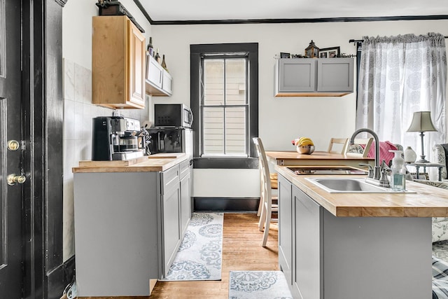 kitchen with gray cabinets, light hardwood / wood-style floors, tasteful backsplash, and wood counters