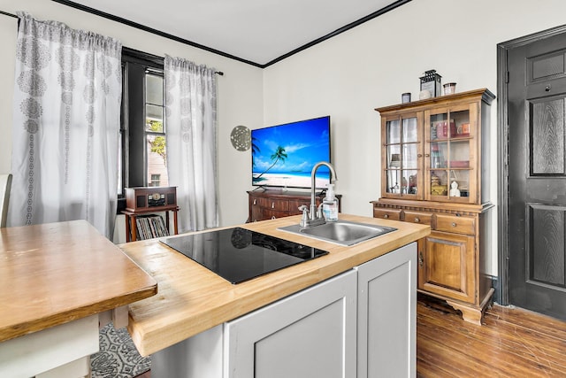 kitchen featuring white cabinetry, light hardwood / wood-style flooring, black electric stovetop, sink, and wood counters