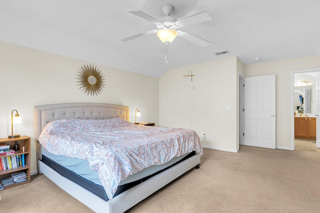 bedroom with ceiling fan, light colored carpet, and ensuite bath