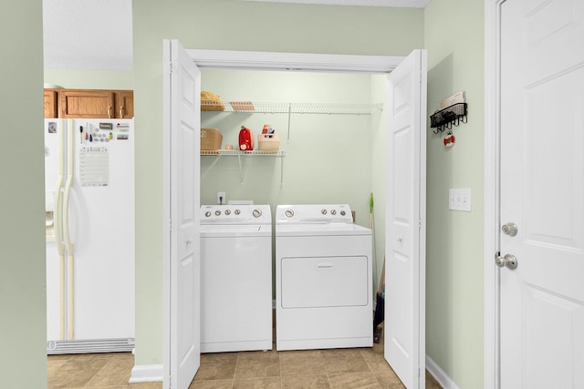 washroom featuring washing machine and clothes dryer, a textured ceiling, and light tile patterned floors