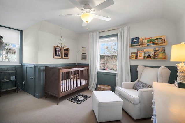 bedroom with a nursery area, carpet, vaulted ceiling, and ceiling fan