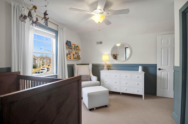 bedroom featuring visible vents, a ceiling fan, a wainscoted wall, carpet, and vaulted ceiling