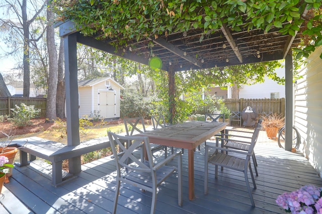 wooden terrace featuring an outbuilding, outdoor dining area, a fenced backyard, and a shed