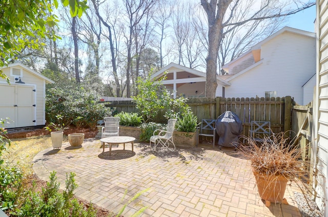 view of patio with an outbuilding, a storage shed, and a fenced backyard