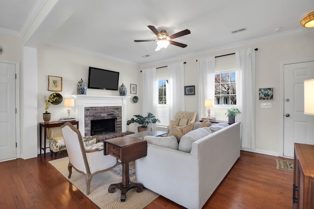 living area with dark wood-style floors, visible vents, a fireplace, and ornamental molding