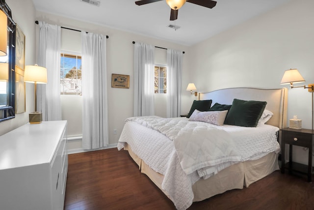 bedroom with dark wood-style floors, multiple windows, ceiling fan, and visible vents